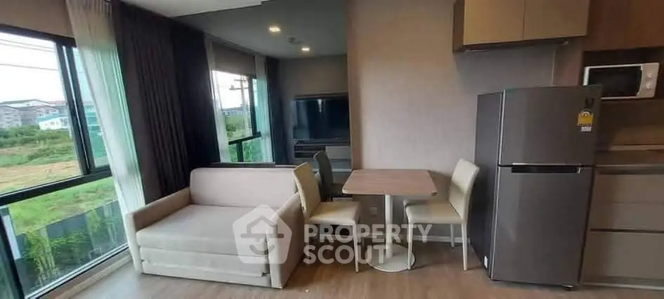 Modern living area with sofa, dining table, and kitchen appliances in a cozy apartment.