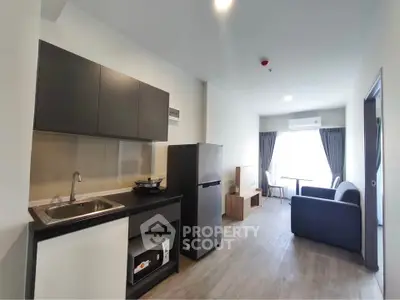 Modern apartment interior with open kitchen and cozy living area, featuring sleek cabinetry and natural light.