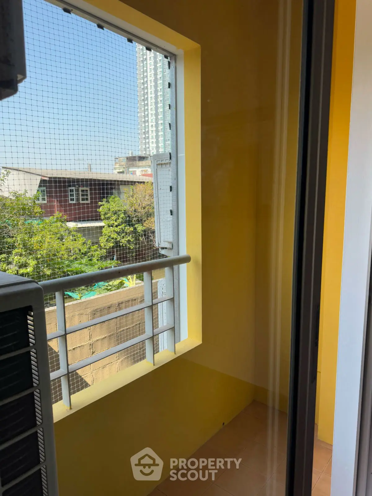 Charming small balcony with safety netting and urban view, perfect for cozy outdoor relaxation.