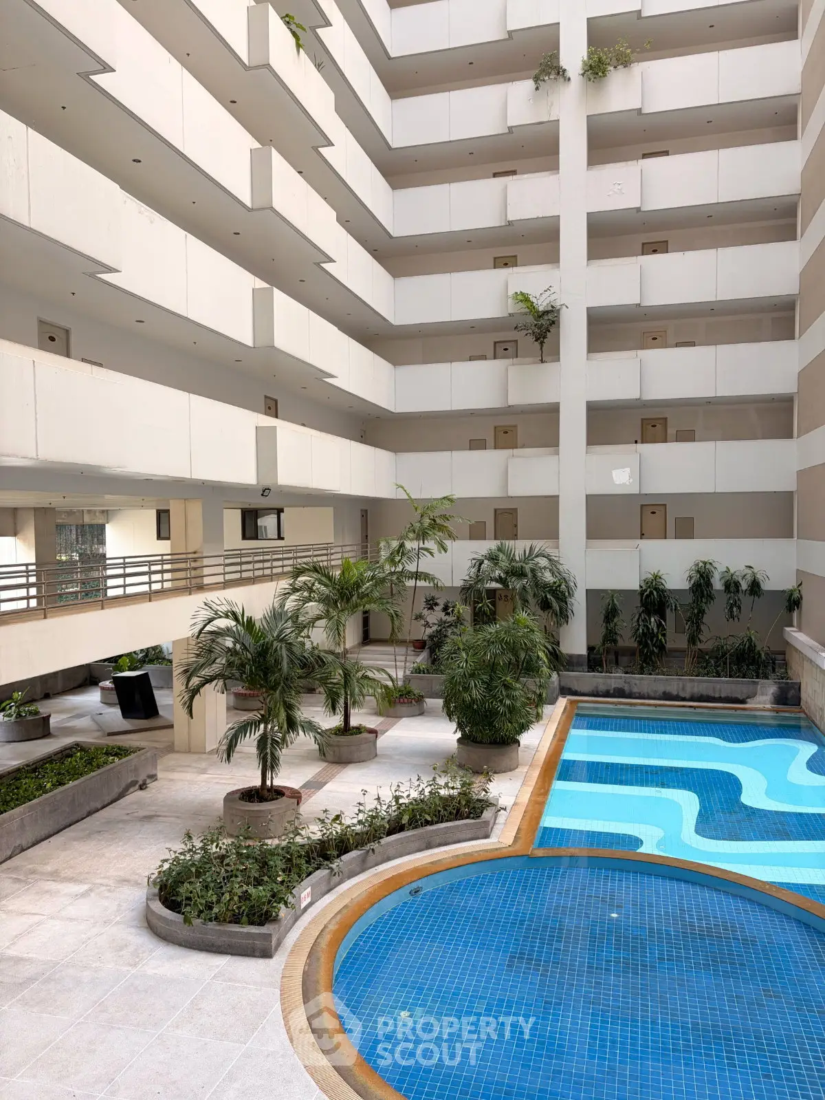 Luxurious apartment complex with indoor pool and lush greenery, offering a serene and modern living experience.