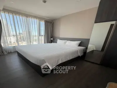 Spacious bedroom with large windows and modern decor in a high-rise apartment.