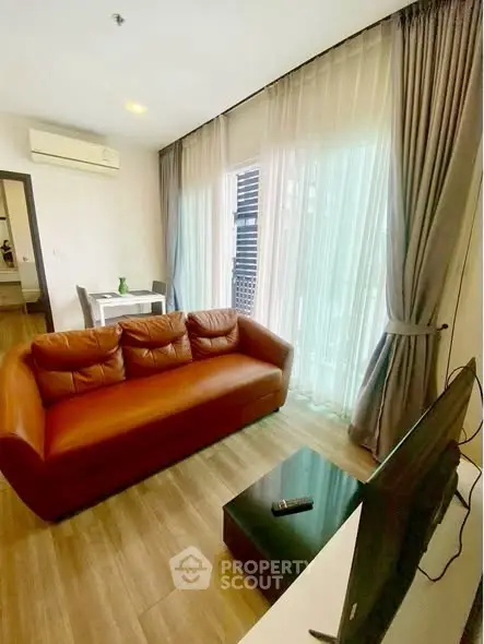 Modern living room with leather sofa, TV, and large window with curtains.