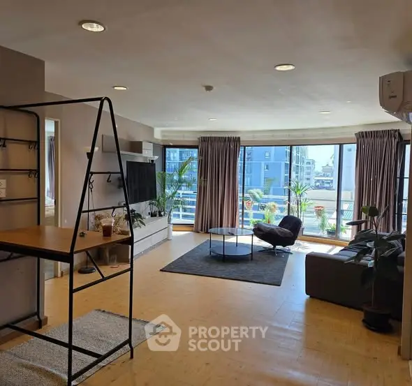 Spacious living room with large windows and modern decor in urban apartment.