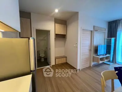 Modern apartment interior with open living area and kitchen, featuring wood flooring and contemporary furnishings.