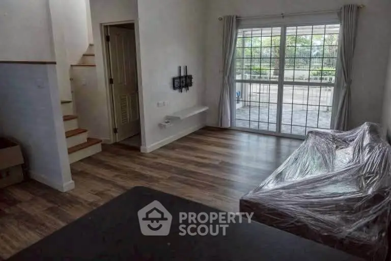 Spacious living room with large windows and staircase, perfect for modern living.