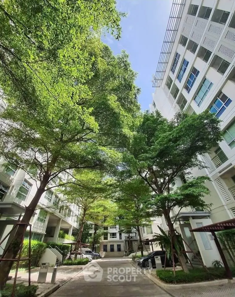 Modern residential building with lush green trees and clear blue sky.
