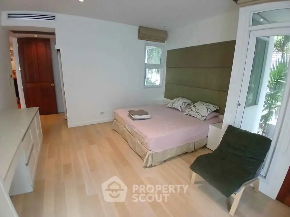 Spacious bedroom with modern decor and large windows for natural light.
