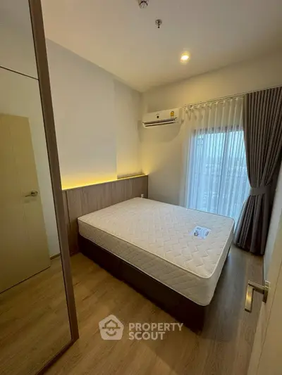 Cozy bedroom with modern design, featuring a comfortable bed and large window with city view.