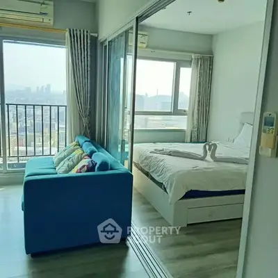 Modern apartment with city view, featuring a cozy living area and bedroom with large windows.
