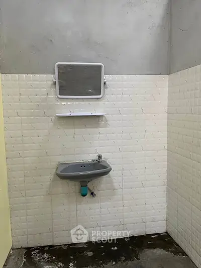 Minimalist bathroom with wall-mounted sink and mirror, featuring white tiled walls.