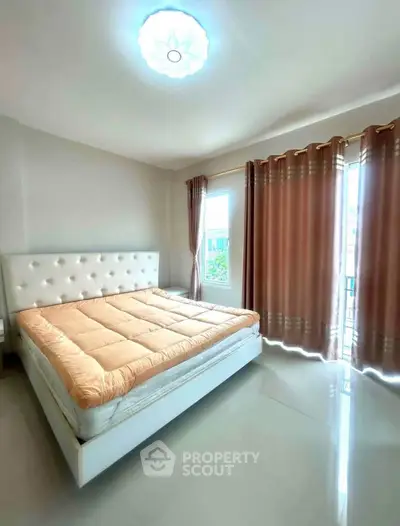 Spacious bedroom with elegant bed and natural light from large windows.