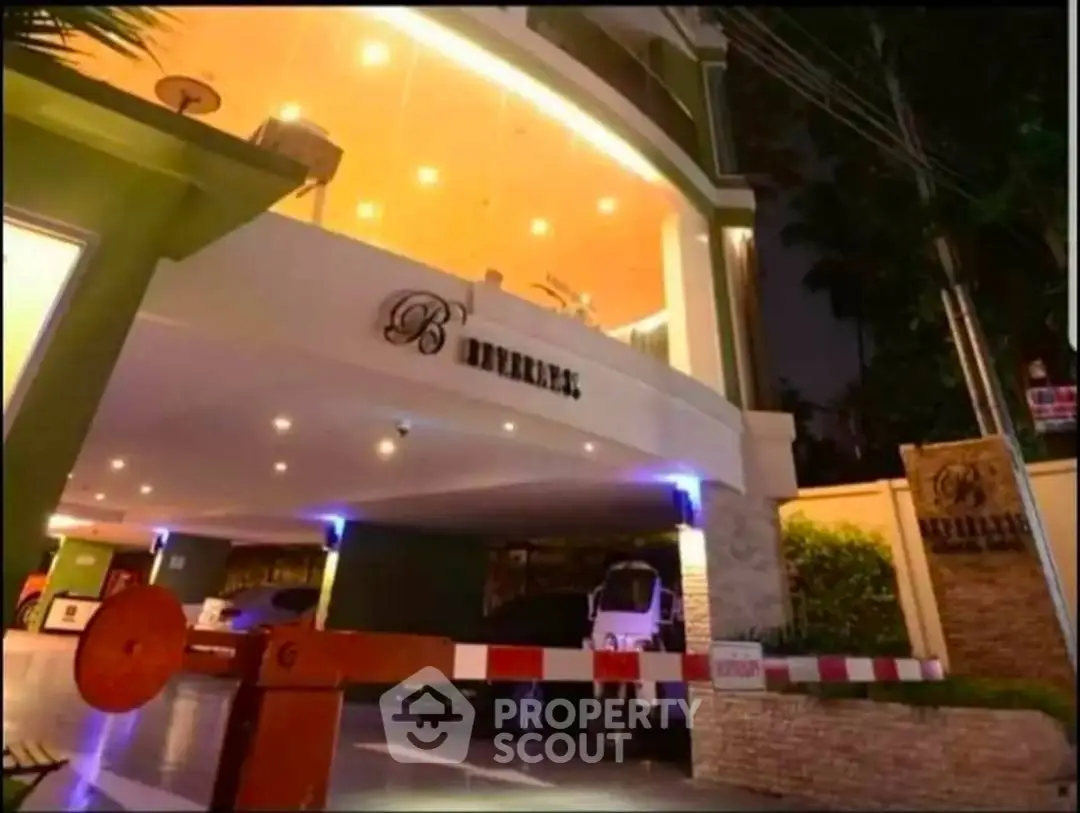 Elegant building entrance with modern lighting and secure parking area at night.