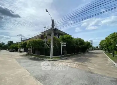 Corner view of a modern residential building with lush greenery and clear skies.