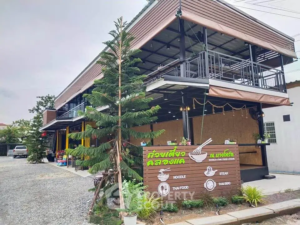 Modern two-story building with restaurant and outdoor seating, ideal for commercial use in a bustling area.