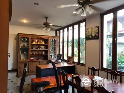 Spacious dining area with ample natural light, elegant wooden furniture, and a view of the lush garden through large windows.