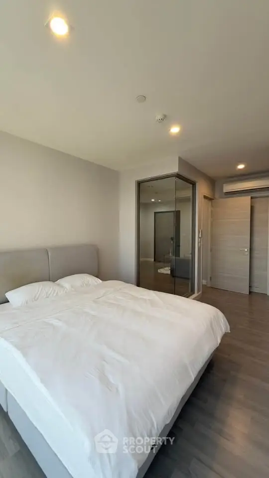 Modern bedroom with sleek design, featuring a large bed and mirrored closet doors, perfect for a cozy retreat.