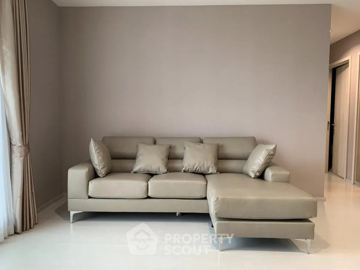 Modern living room with sleek beige sectional sofa and elegant curtains, perfect for stylish urban living.