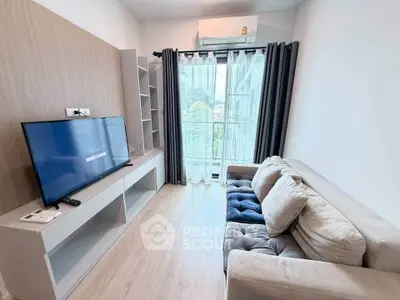 Modern living room with sleek TV setup and cozy sofa, featuring large window for natural light.