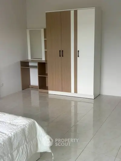 Spacious bedroom with modern wardrobe and tiled flooring in a minimalist design.
