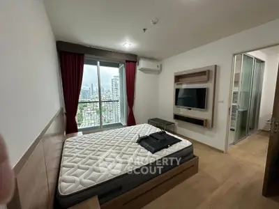 Modern bedroom with city view, featuring a mounted TV and stylish decor.