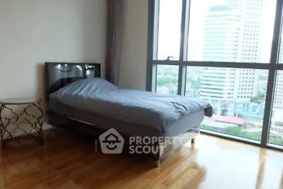 Spacious bedroom with city view and hardwood floors in modern apartment.