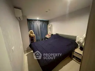Cozy bedroom with dark bedding and soft lighting, featuring a teddy bear and modern decor.