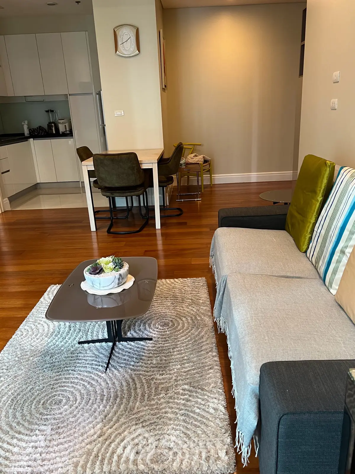 Stylish open-plan living room with modern kitchen and cozy dining area, featuring elegant hardwood floors and chic decor.