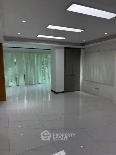 Spacious modern living room with sleek tile flooring and large windows.