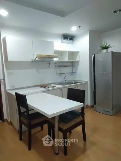 Modern kitchen with sleek design, featuring a compact dining area and stainless steel appliances.