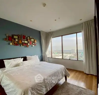Spacious bedroom with large window offering stunning city views, modern decor, and cozy ambiance.