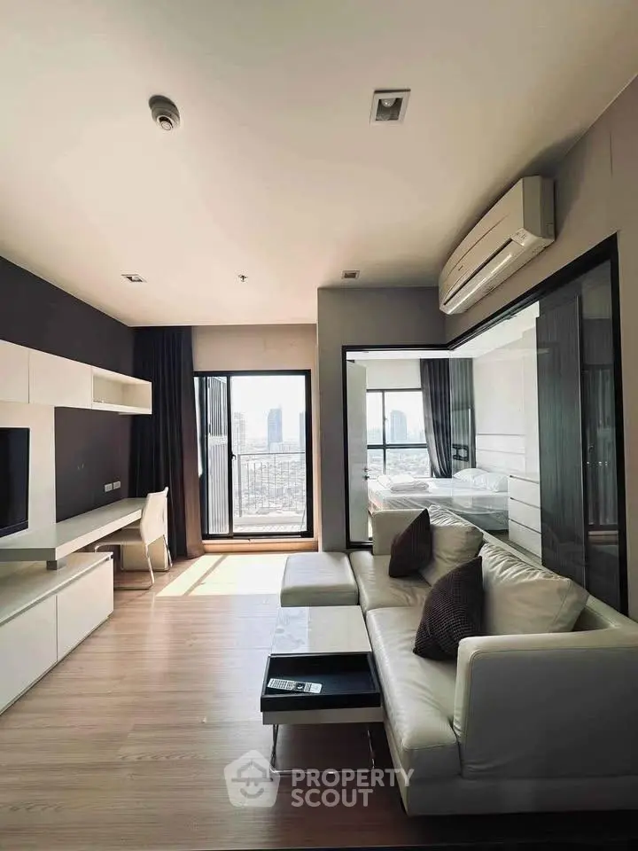 Modern living room with sleek furniture and city view from balcony, featuring a cozy sofa and stylish decor.