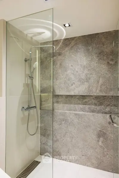 Modern bathroom with sleek glass shower and elegant stone tiles
