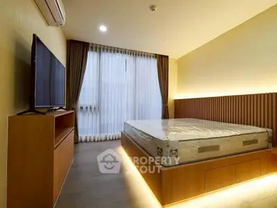 Modern bedroom with sleek design, featuring a large bed, ambient lighting, and a wall-mounted TV.