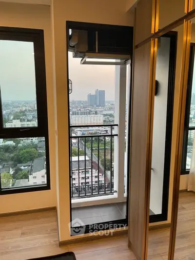 Stunning city view from modern apartment balcony with floor-to-ceiling windows and sleek interior design.