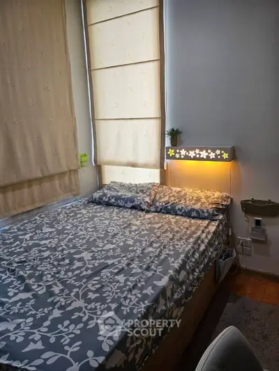 Cozy bedroom with floral bedding and soft lighting, perfect for relaxation.