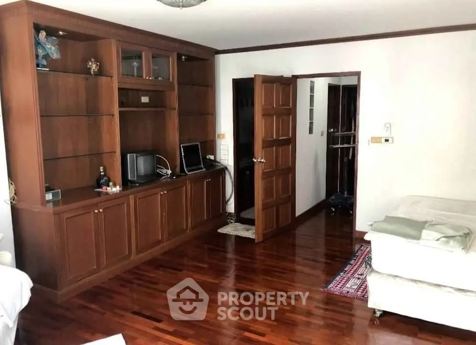 Spacious living room with wooden flooring and built-in shelving, perfect for cozy family gatherings.