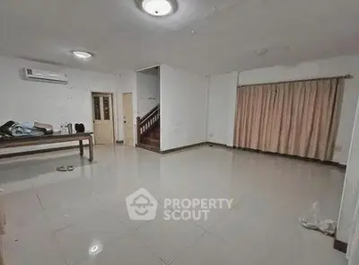 Spacious empty living room with tiled floor and staircase, ideal for customization.