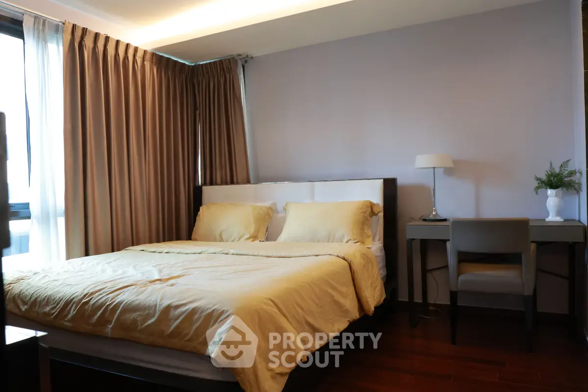 Elegant bedroom with cozy bed, modern desk, and natural light from large windows.
