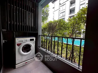 Charming balcony with washing machine overlooking lush greenery and pool view.