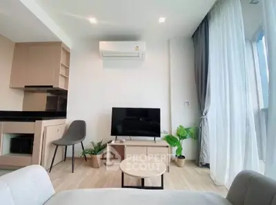 Modern living room with sleek furniture and natural light, featuring a TV and air conditioning.