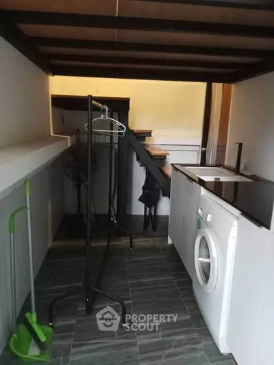 Compact laundry area with washing machine and storage under stairs