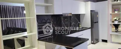 Modern kitchen with sleek black countertops and white cabinetry, featuring a built-in oven and stainless steel fridge.