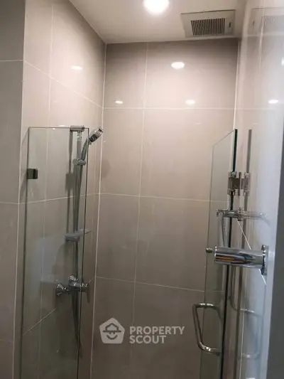 Modern bathroom with glass shower enclosure and sleek tile design.