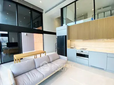 Modern open-plan living room with sleek kitchen and large windows in a stylish apartment.