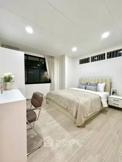Spacious modern bedroom with elegant decor and large window for natural light.