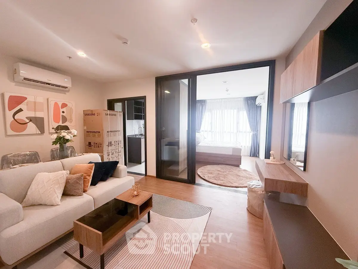 Modern living room with stylish decor and open view into a cozy bedroom, featuring elegant furniture and warm lighting.