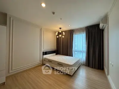 Spacious bedroom with modern lighting and large window in elegant apartment.