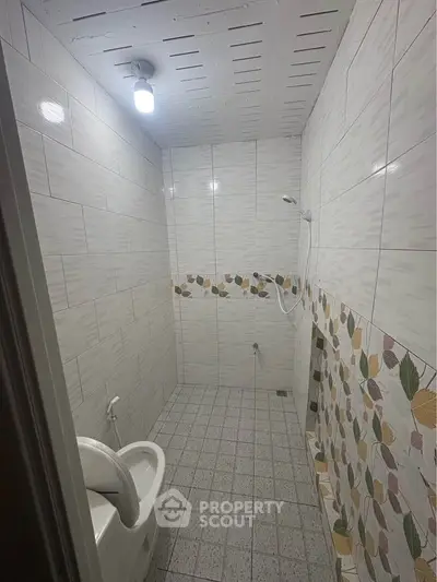 Compact bathroom with tiled walls and ceiling light