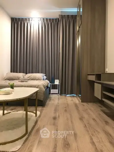 Modern bedroom with stylish decor and wooden flooring, featuring a cozy bed and elegant curtains.