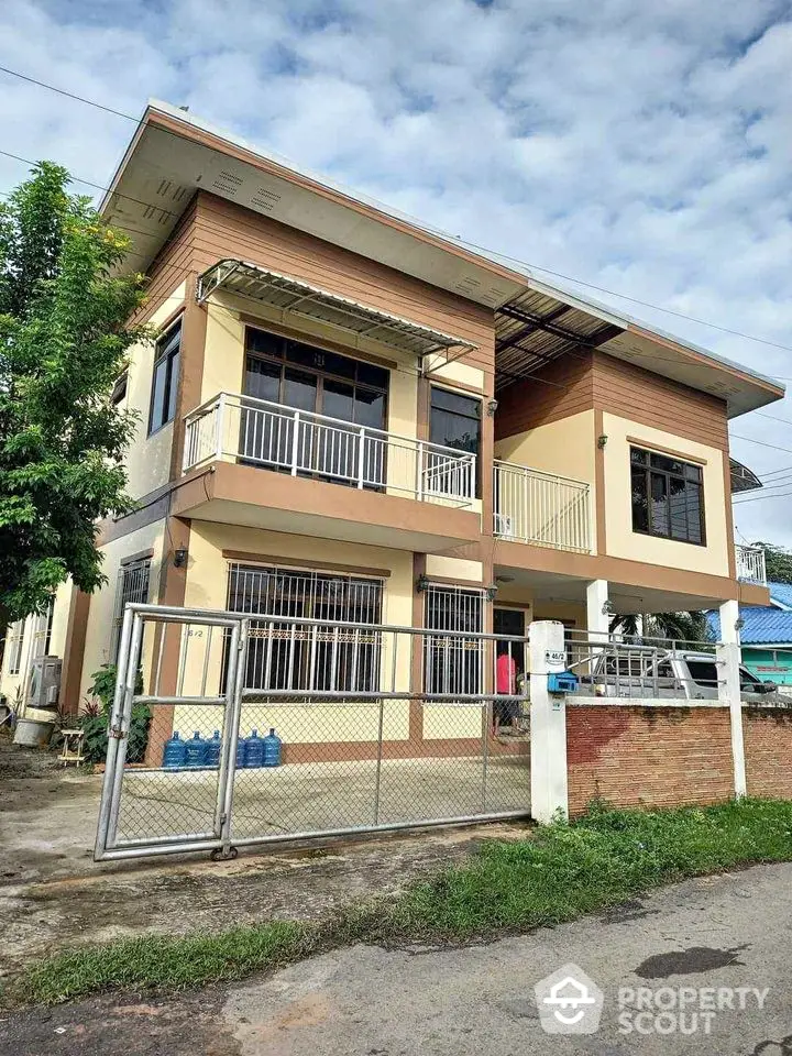 Modern two-story house with spacious balcony and gated entrance in a serene neighborhood.